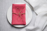 Salmon linen napkin tied with jute twine on a white plate