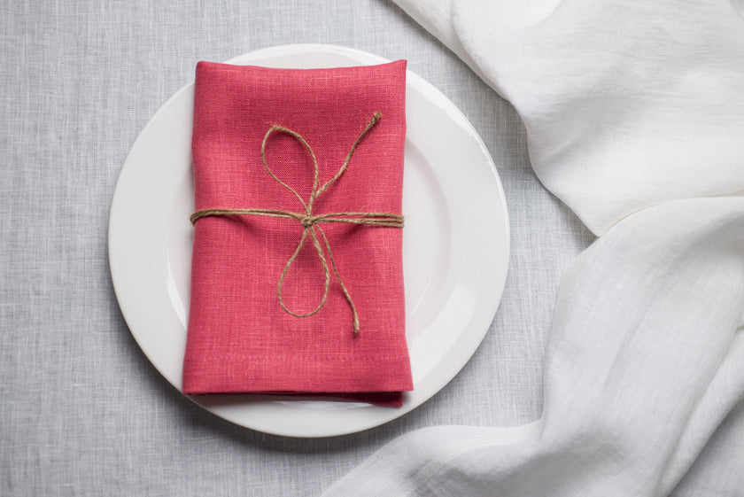 Salmon linen napkin tied with jute twine on a white plate