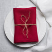 Wine linen napkin tied with jute twine on a white plate