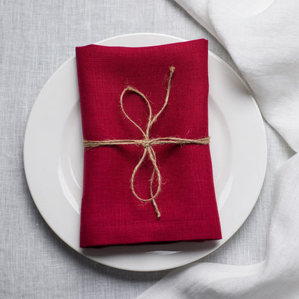 Wine linen napkin tied with jute twine on a white plate