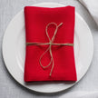 Red linen napkin tied with jute twine on a white plate