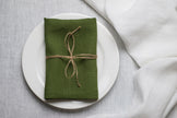 Green linen napkin tied with jute twine on a white plate