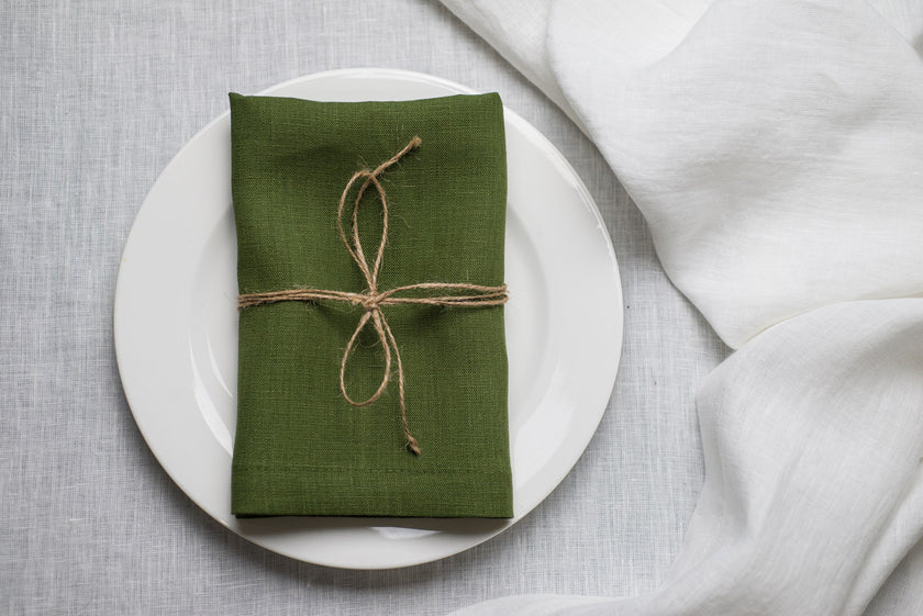 Green linen napkin tied with jute twine on a white plate