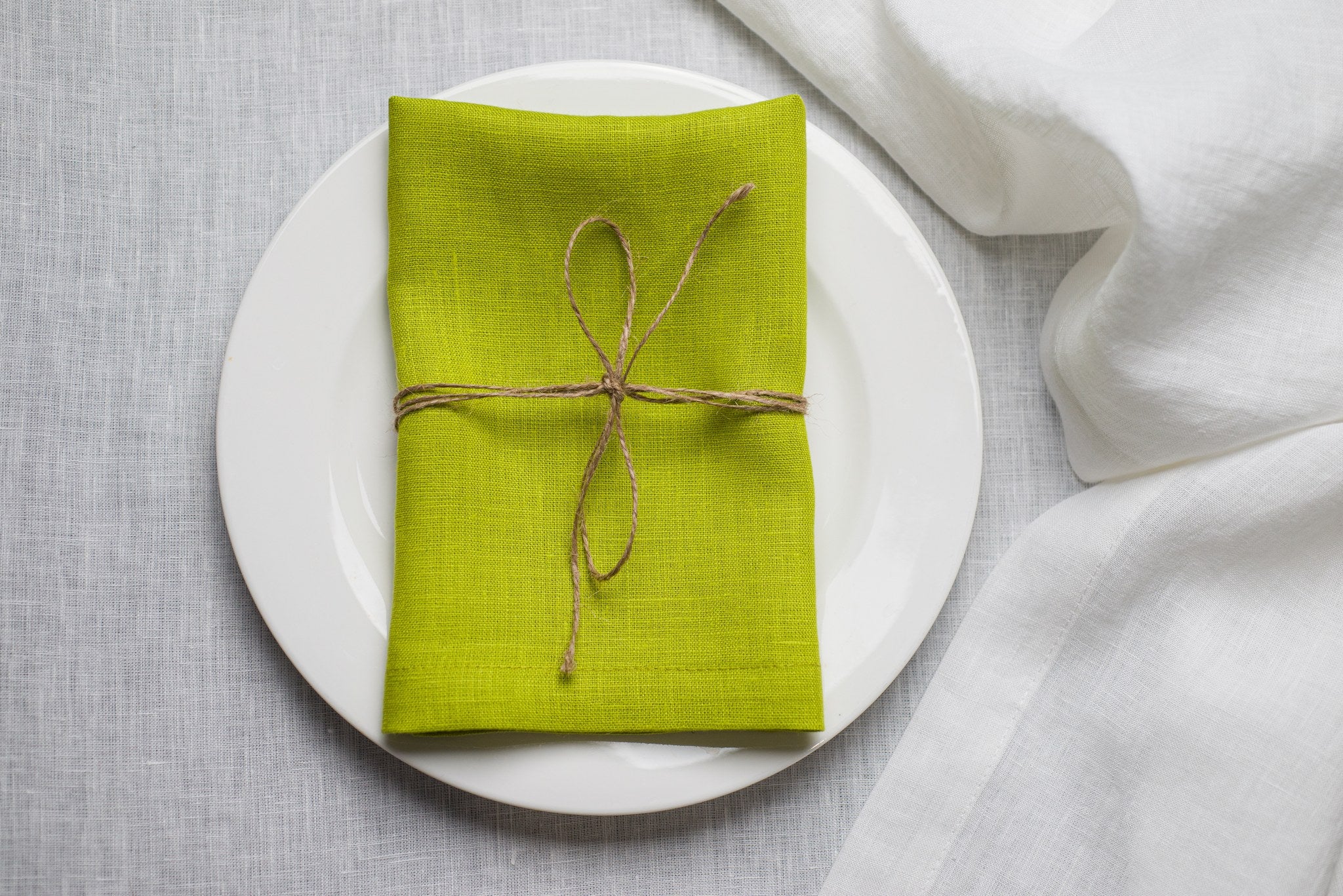 Lime linen napkin tied with jute twine on a white plate
