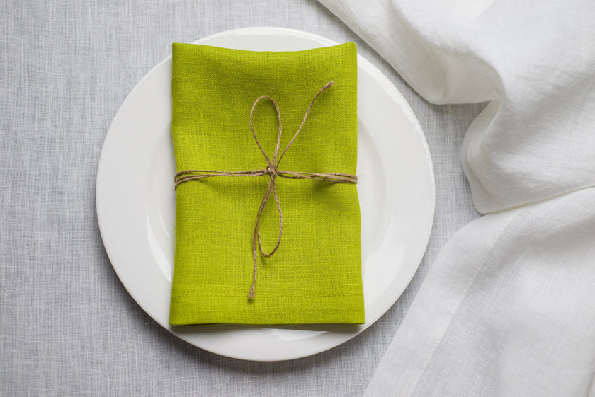 Lime linen napkin tied with jute twine on a white plate