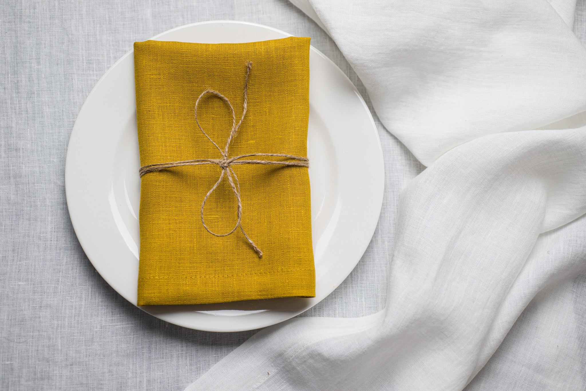 Corn linen napkin tied with jute twine on a white plate