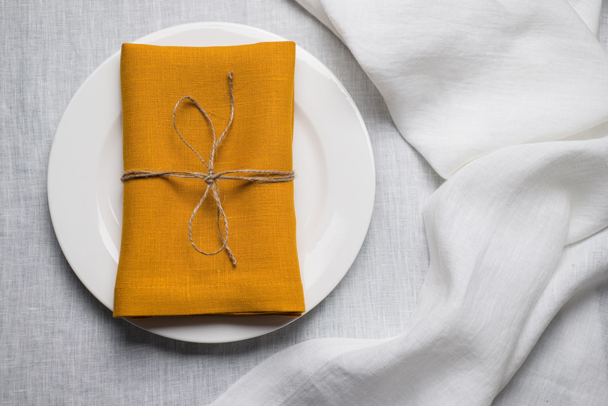 Canary linen napkin tied with jute twine on a white plate