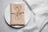 Sand linen napkin tied with jute twine on a white plate