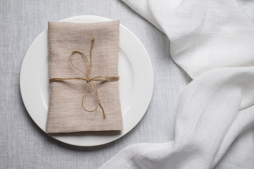 Natural Beige linen napkin tied with jute twine on a white plate