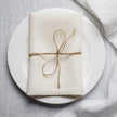 Milk linen napkin tied with jute twine on a white plate