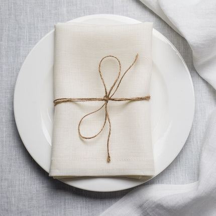 Milk linen napkin tied with jute twine on a white plate