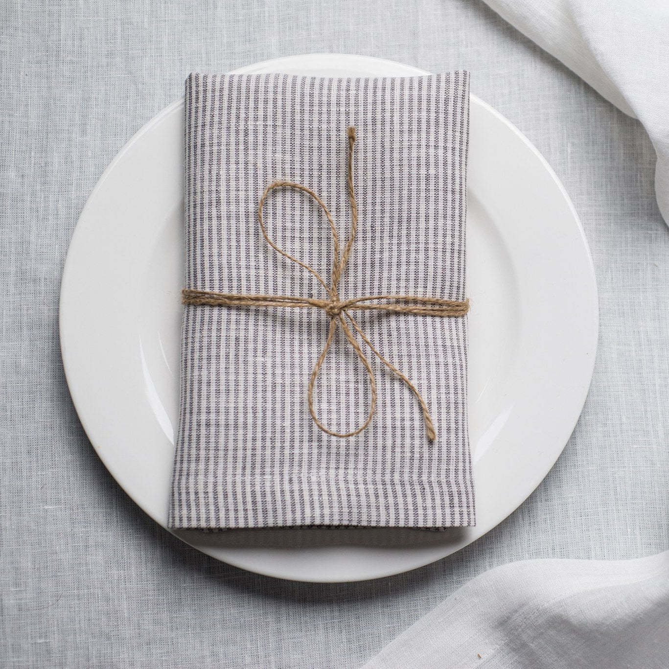 New Striped linen napkin tied with jute twine on a white plate