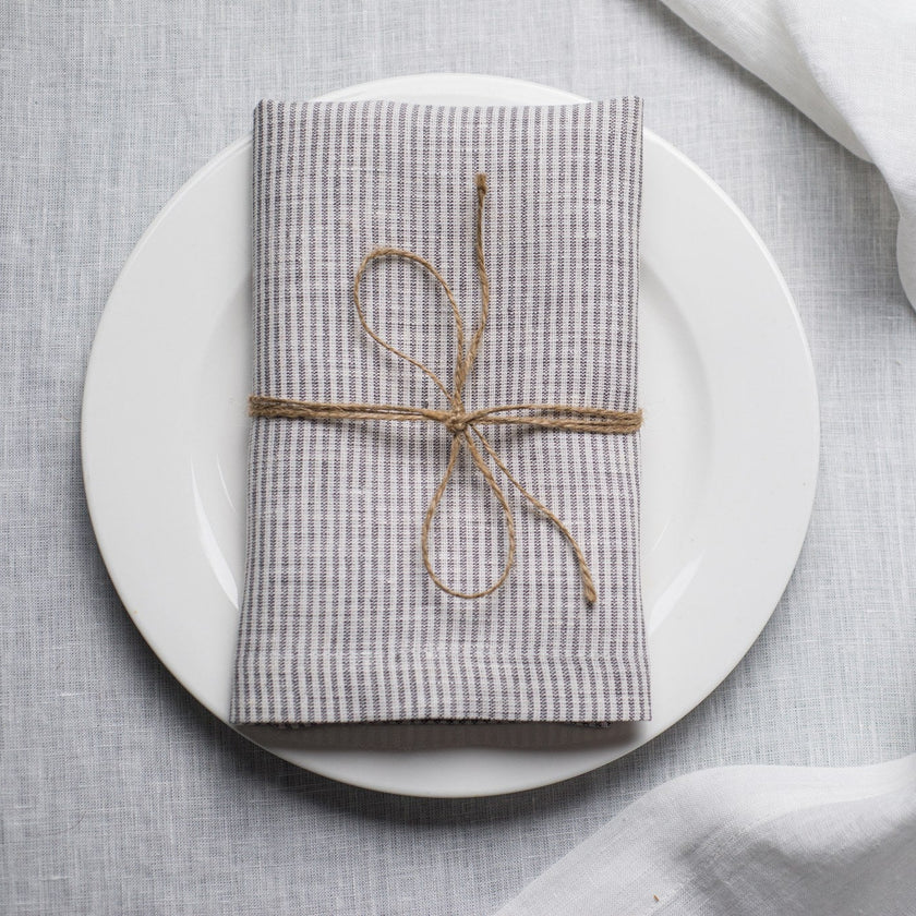 New Striped linen napkin tied with jute twine on a white plate