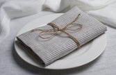 New Striped linen napkin tied with jute twine on a white plate, side view