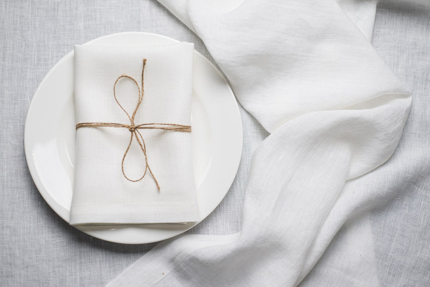 White linen napkin tied with jute twine on a white plate