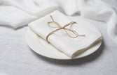 White linen napkin tied with jute twine on a white plate, side view