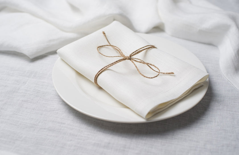 White linen napkin tied with jute twine on a white plate, side view
