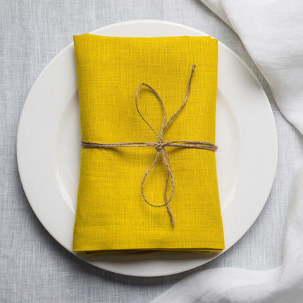 Lemon linen napkin tied with jute twine on a white plate