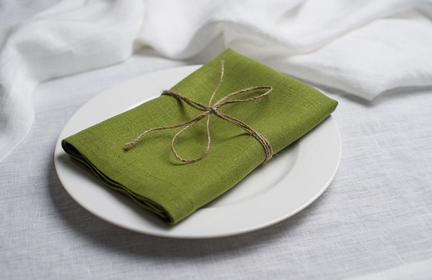 Pear linen napkin tied with jute twine on a white plate, side view