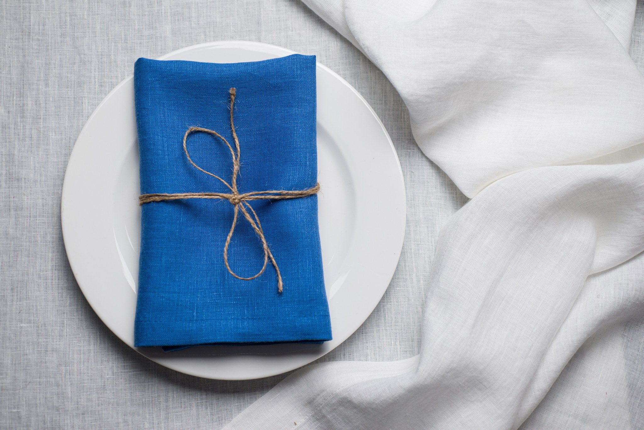 Electric linen napkin tied with jute twine on a white plate