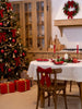 White round linen tablecloth with red linen napkins beside a lit Christmas tree