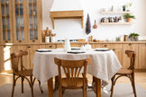 Natural linen tablecloth on a wooden dining table with chairs in a cozy kitchen interior.