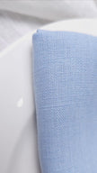 Video: close-up of a folded sky blue linen napkin on a white plate