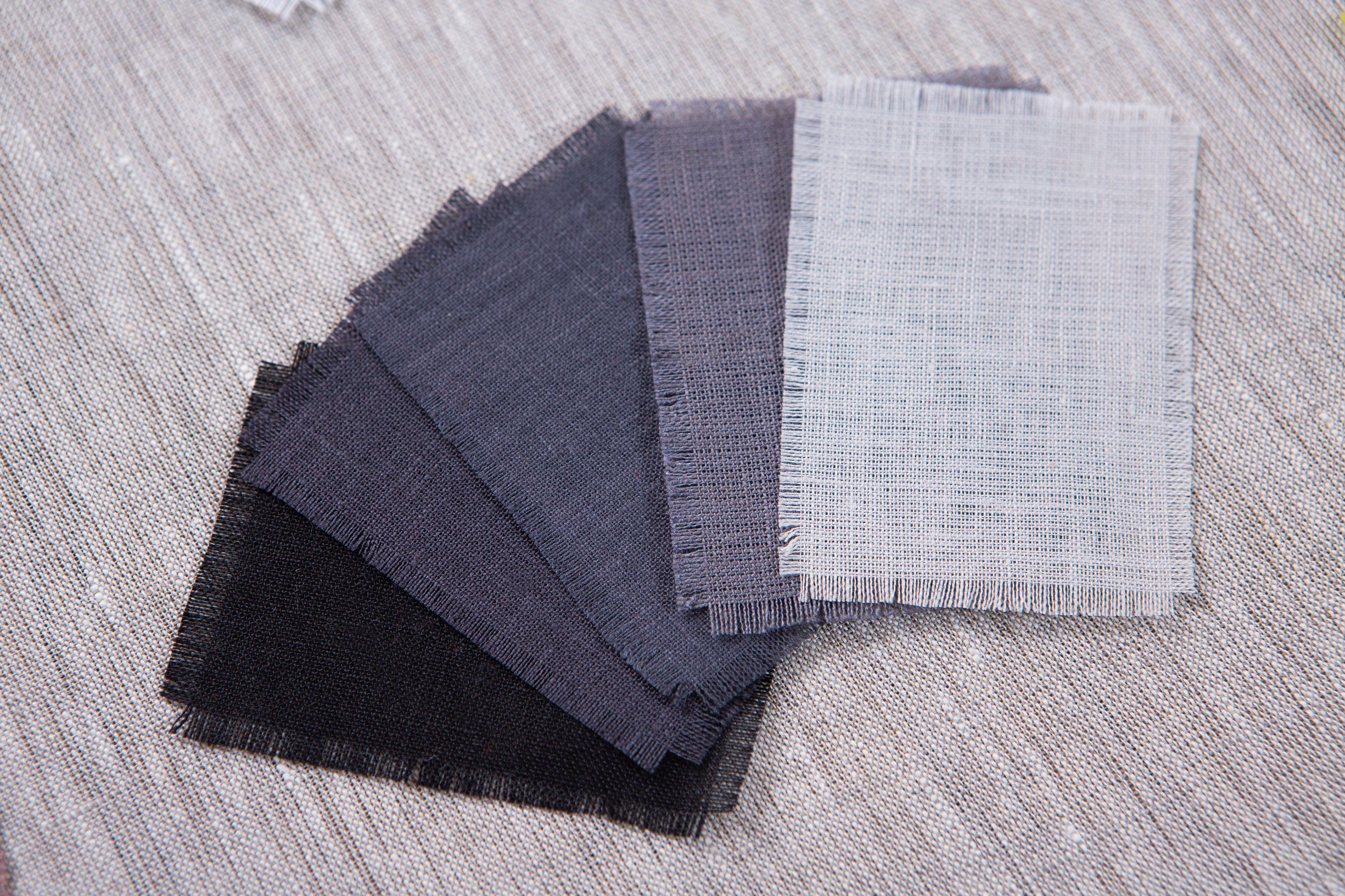 A variety of organic linen fabric samples of CoolLinen.store in a grey shades